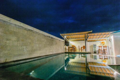 a swimming pool next to a building with a house at D'Yuki Huts Lembongan in Nusa Lembongan