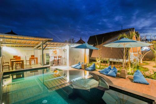 a swimming pool with two umbrellas next to a house at D'Yuki Huts Lembongan in Nusa Lembongan