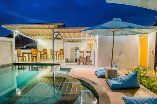 a pool with an umbrella next to a house at D'Yuki Huts Lembongan in Nusa Lembongan