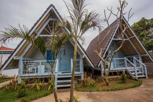 a blue house with a palm tree in front of it at D'Yuki Huts Lembongan in Nusa Lembongan