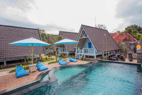 a swimming pool with blue pillows and umbrellas at D'Yuki Huts Lembongan in Nusa Lembongan