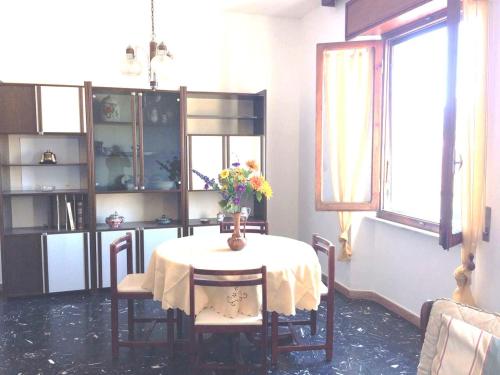 a dining room table with a vase of flowers on it at Via Roma 44 in Follonica