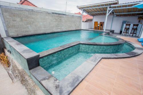a large swimming pool with a stone wall at D'Yuki Huts Lembongan in Nusa Lembongan
