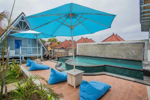 a large blue umbrella sitting next to a swimming pool at D'Yuki Huts Lembongan in Nusa Lembongan