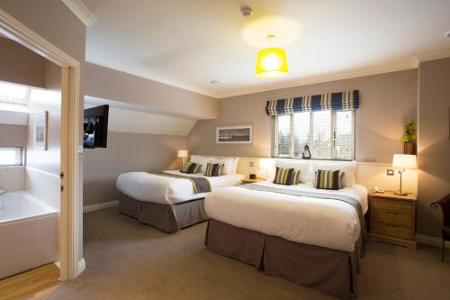 two beds in a hotel room with a bathroom at Breckland Lodge in Attleborough
