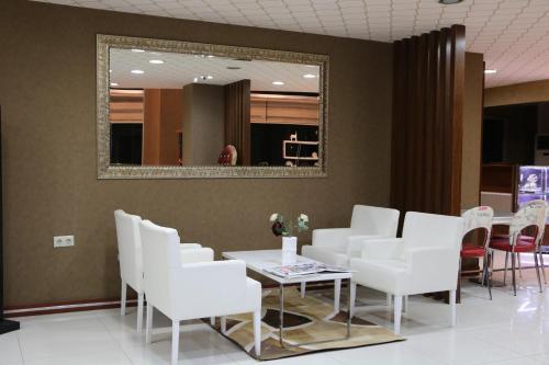 a waiting room with white chairs and a table and a mirror at Business Grand Hotel in Ankara