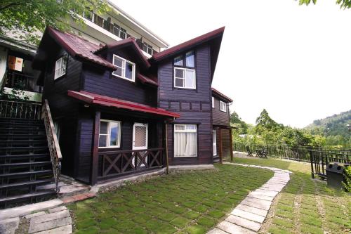 una casa negra con césped delante en Yun Meng Xianjing Homestay, en Renai