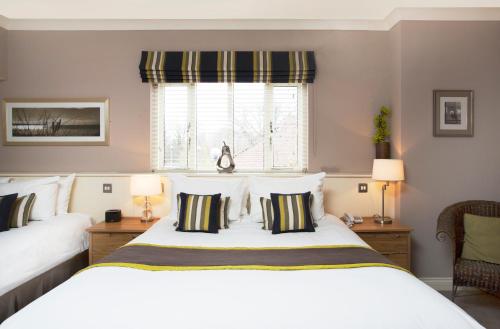 a bedroom with a large white bed with two pillows at Breckland Lodge in Attleborough