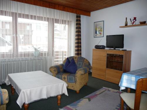 a living room with a tv and a chair and a table at Landhaus Lederer in Bischofsgrün
