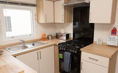 a kitchen with a sink and a stove top oven at Mersea Island by Away Resorts in Colchester