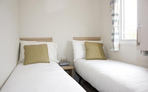 two twin beds in a room with a window at Mersea Island by Away Resorts in Colchester