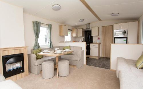 a living room with a table and a kitchen at Mersea Island by Away Resorts in Colchester