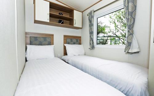 two beds in a small room with a window at Mersea Island by Away Resorts in Colchester
