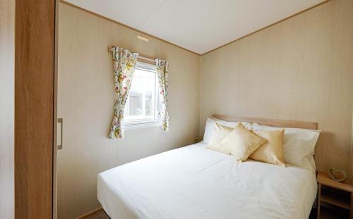 a bedroom with a white bed with a window at Mersea Island by Away Resorts in Colchester
