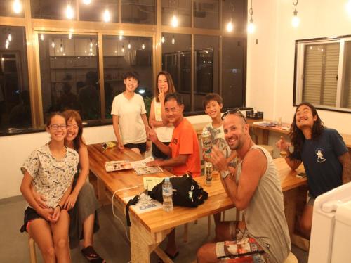 a group of people sitting around a wooden table at Ishigaki Guesthouse HIVE in Ishigaki Island