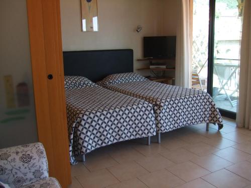 um quarto com uma cama, uma televisão e uma porta em The Dina Palace. em Villefranche-sur-Mer