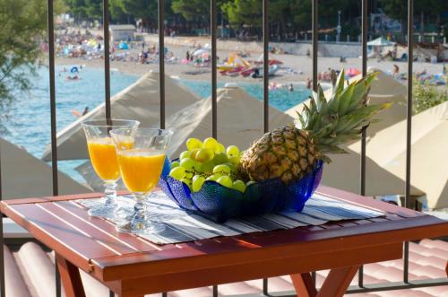 a table with a bowl of fruit and two glasses of orange juice at Apartment Primosten Adiomare in Primošten
