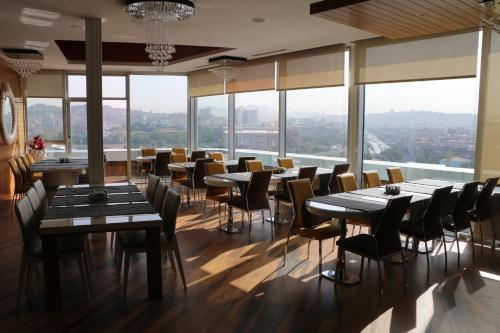 a restaurant with tables and chairs and large windows at Business Grand Hotel in Ankara