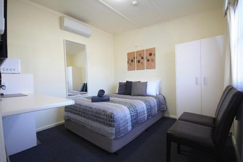 a bedroom with a bed with a desk and a chair at Hi Way Motor Inn in Yass