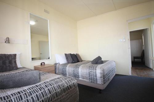 a hotel room with two beds and a mirror at Hi Way Motor Inn in Yass