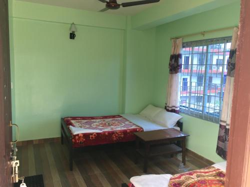 a small room with two beds and a window at Harry Guest House & Restaurant in Pokhara