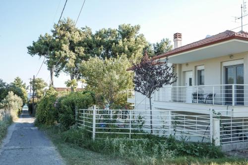 a white house with a fence next to a road at Nektarios Garenias Kipoupoli in Nea Kalikratia