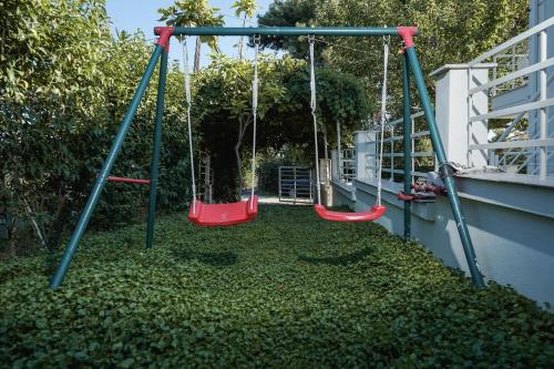 a playground with two swings in a yard at Nektarios Garenias Kipoupoli in Nea Kalikratia