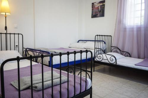 a room with three bunk beds with purple sheets at Nektarios Garenias Kipoupoli in Nea Kalikratia