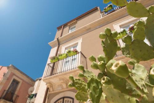 a building with two balconies with flowers on it at Le tre muse in Siracusa