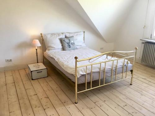 a bedroom with a bed and a lamp on a wooden floor at Beautiful apartment in a historic villa in Hattingen
