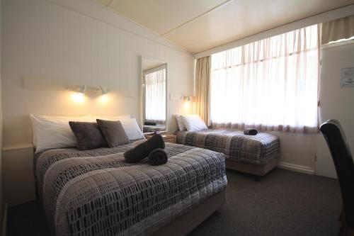 a bedroom with two beds and a cat laying on a bed at Hi Way Motor Inn in Yass