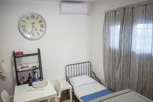 a small room with a bed and a clock on the wall at Nektarios Garenias Kipoupoli in Nea Kalikratia