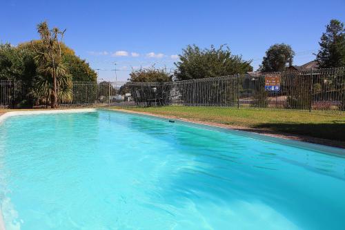 a large blue swimming pool in front of a fence at Hi Way Motor Inn in Yass
