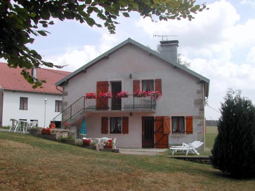 a white house with red flowers on a balcony at Gîte Les Hirondelles in Plombières-les-Bains