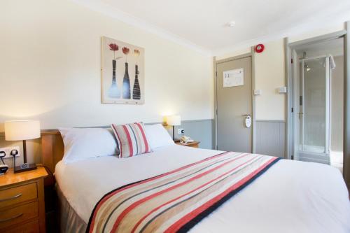 a bedroom with a white bed with a striped blanket at Breckland Lodge in Attleborough