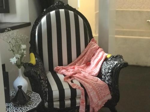 a black chair with a blanket on top of it at Dar Kandi in Marrakech