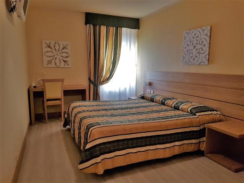 1 dormitorio con cama, mesa y ventana en Albergo Fiorita, en Bardolino