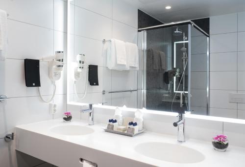 a white bathroom with a sink and a mirror at Thon Hotel Storo in Oslo