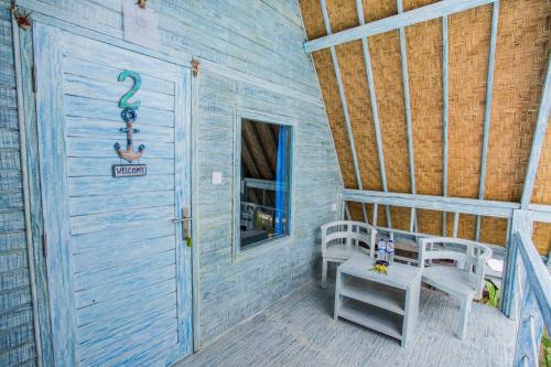 a porch of a house with two chairs and a table at D'Yuki Huts Lembongan in Nusa Lembongan