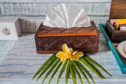a wooden box with a yellow flower on a table at D'Yuki Huts Lembongan in Nusa Lembongan