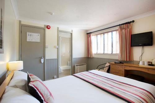 a bedroom with a bed and a desk and a television at Breckland Lodge in Attleborough