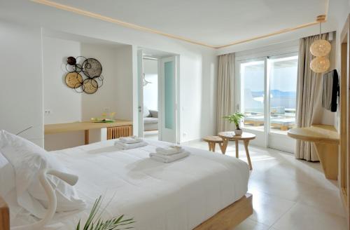 a white bedroom with a large bed and a balcony at Anax Resort and Spa in Agios Ioannis Mykonos