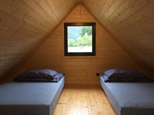 two beds in a attic room with a window at Domek letniskowy in Wünschelburg