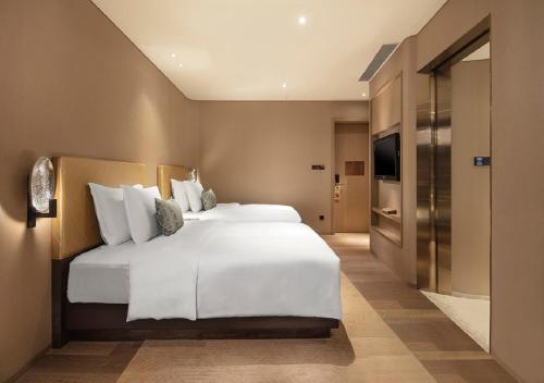 a large white bed in a hotel room at Grand Bay Hotel Zhuhai in Zhuhai