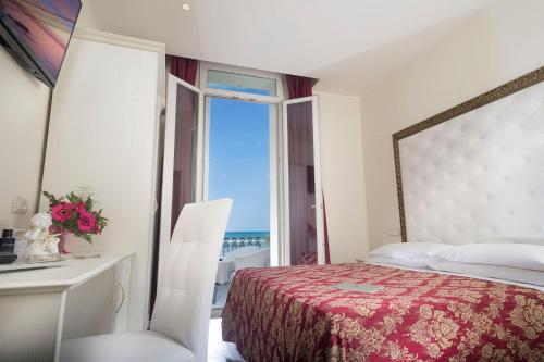a bedroom with a bed and a desk and a window at Hotel Lido in Rimini