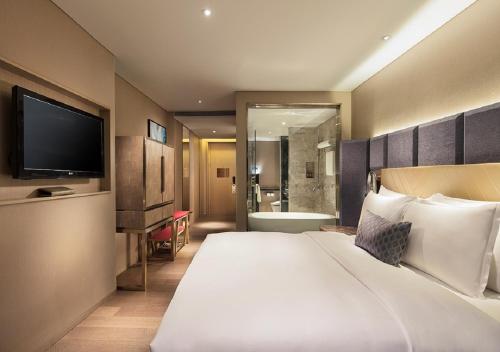a hotel room with a large bed and a television at Grand Bay Hotel Zhuhai in Zhuhai