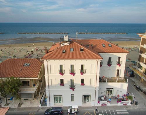 a white building with red roofs next to a beach at Hotel Lido in Rimini
