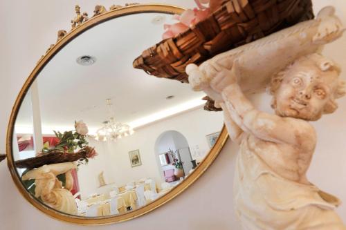 a mirror with a statue of a angel holding a basket at Hotel Lido in Rimini