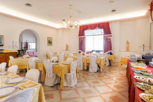 a banquet hall with tables and chairs and a chandelier at Hotel Lido in Rimini