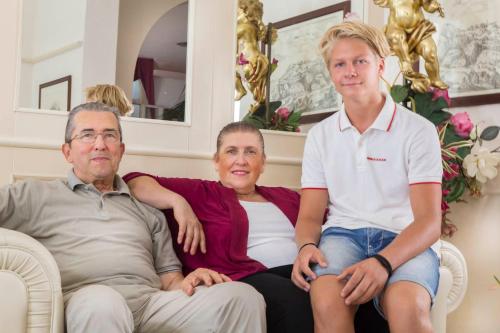 a man and a woman sitting on a couch with a boy at Hotel Lido in Rimini